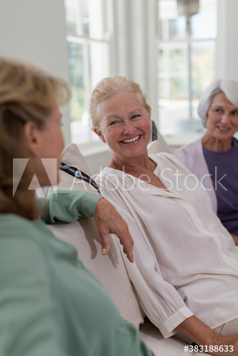 Happy senior women friends talking on sofa