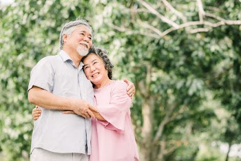 Happy smile senior Asian couple enjoying quality time together and holding each other in the park.