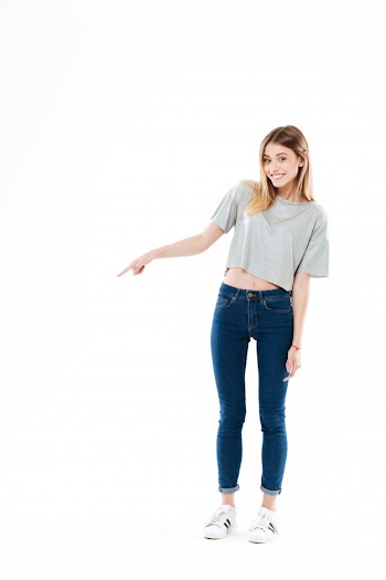 Happy smiling young woman standing and pointing Free Photo