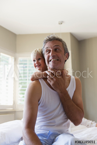 Happy son hugging father on bed