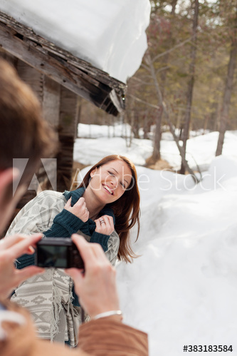 Happy woman posing for photograph outside snowy cabin