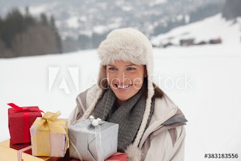 Happy woman with Christmas gifts in snowy field
