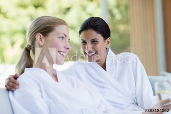 Happy women friends in bathrobes relaxing in spa