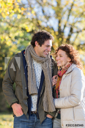 Happy young couple arm in arm in autumn park