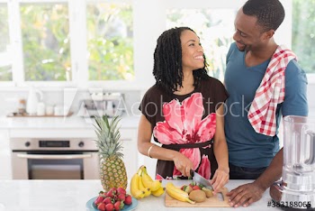 Happy young couple cutting fresh fruit in kitchen