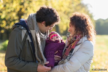 Happy young couple holding baby daughter in sunny park