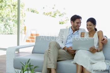 Happy young couple on sofa with laptop