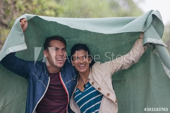 Happy young couple under blanket in rain