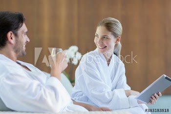Happy young couple with digital tablet in bathrobes at spa