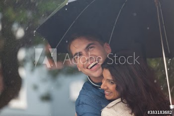 Happy young couple with umbrella in rain