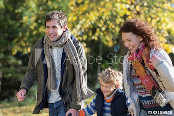 Happy young family running in sunny autumn park