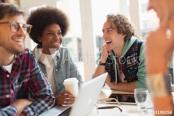 Happy young friends drinking coffee and working in cafe