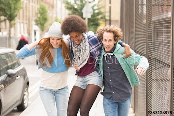 Happy young friends running on city sidewalk