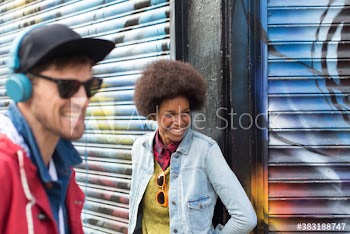 Happy young man and woman laughing against graffiti wall