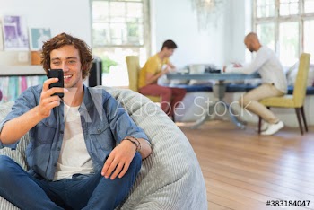 Happy young man using smart phone in beanbag chair