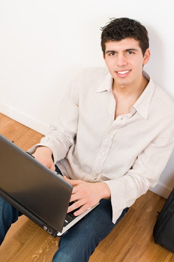 Happy young man working on his laptop with casual clothing