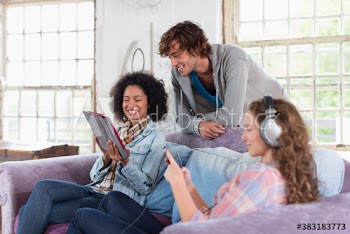 Happy young roommates with digital tablet hanging out in living room