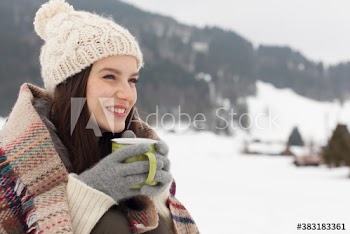 Happy young woman drinking hot cocoa in snow