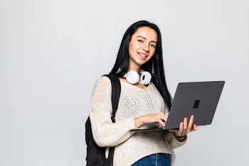 Happy young woman holding laptop and  over gray wall Free Photo