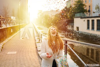 Happy young woman playing with confetti on street