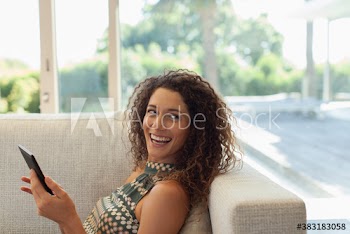 Happy young woman using digital tablet on sofa
