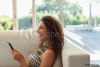 Happy young woman using digital tablet on sofa