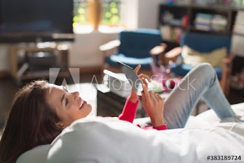 Happy young woman using digital tablet on sofa