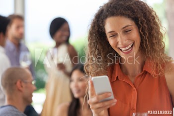 Happy young woman using smart phone at party
