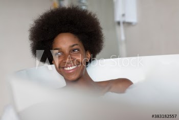 Happy young woman with afro enjoying bubble bath