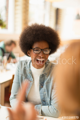 Happy young woman with afro laughing in cafe