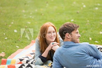 Happy young woman with boyfriend on blanket in park