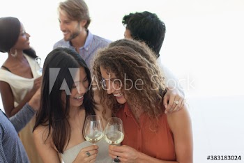 Happy young women friends enjoying white wine at party