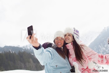 Happy young women friends taking selfie in snow