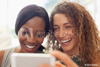 Happy young women friends using digital tablet