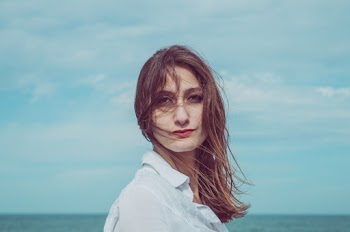 Headshot Of A Woman With Long Disheveled Hair In White Shirt