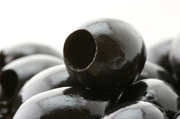 Heap of oil black olives close-up on white background.