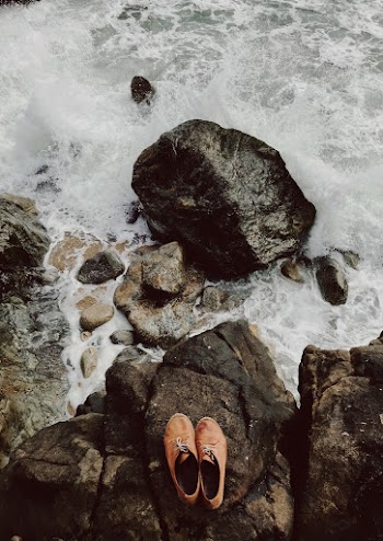 High Angle Photo of Shoes on Rocky Shore