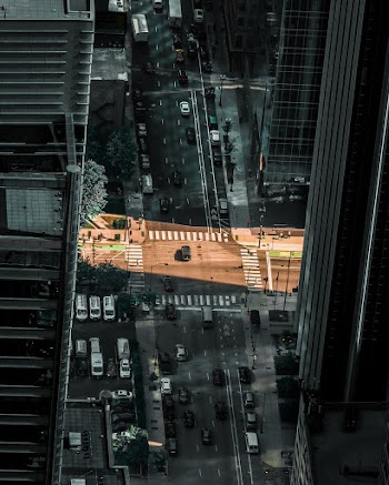 High Angle Photo of Vehicles on Road Between High Rise Buildings