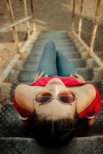 High Angle Photo of Woman Sitting on Metal Staircase