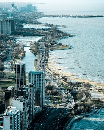 High Angle Photography of a Highway Near Body of Water and Buildings
