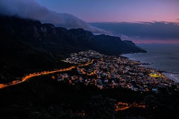 high-angle photography of city near smoky mountain and body of water during sunset
