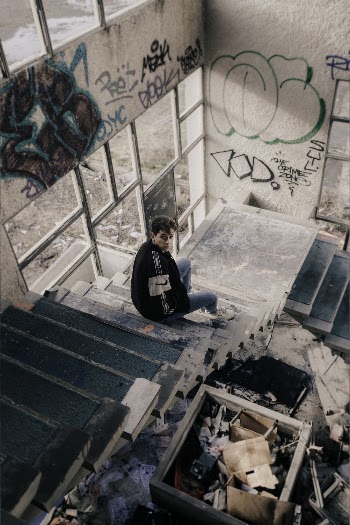 High-angle Photography of Man Sitting on Concrete Staircase