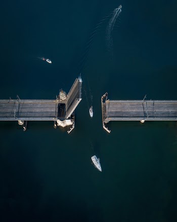 High-angle Photography of White Sailboat Crossing Bridge