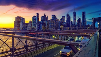 High Angle Shot Of Vehicles On A Bridge With The View Of The Cityscape At Dusk