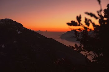high-angle silhouette photography of mountain ranges with body of water in between during golden hour