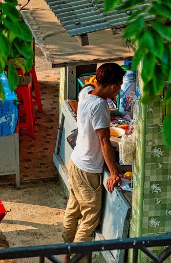 High Angle Sot Of A Man Standing In Front Of A Small  Wooden Stall