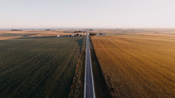 high angle view of gray roadway surrounded by grass field