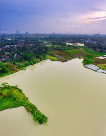 High View of Brown Water Surface, Green Lands, and Houses