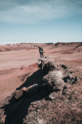 Hiker Peaks Over Rocky Edge