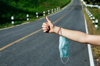 Hitchhiker holding medical mask on a highway